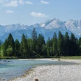 Loisach mit Blick auf die Alpspitze Klarer Fluss vor dichtem Wald mit markantem Gebirgsmassiv unter blauem Himmel