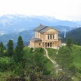 Schachenschloss Holzhaus auf bewaldetem Bergrücken mit weiten Bergketten im Hintergrund