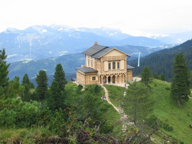 Schachenschloss Holzhaus auf bewaldetem Bergrücken mit weiten Bergketten im Hintergrund