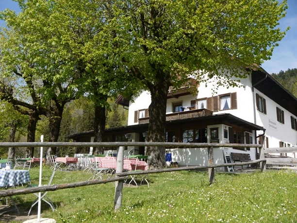 Hannselabauer Vordergraseck Außenbereich eines Gasthauses mit schattigen Bäumen und Tischen auf einer Wiese vor dem Gebäude
