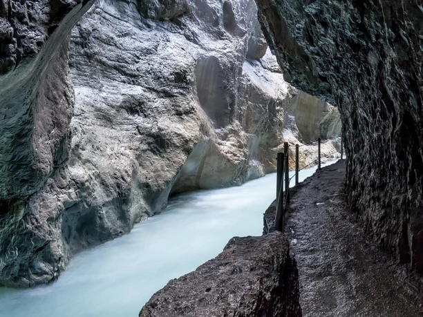 Weg durch die Partnachklamm Schmaler Felsweg entlang eines milchigen Wildbachs in der engen Partnachklamm