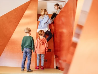 Kinder steigen auf die Rutsche in Murgels Spielhaus