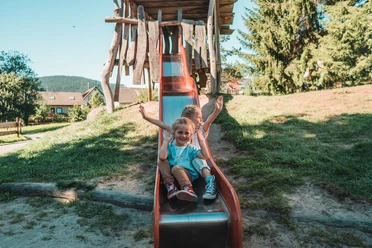 Zwei Kinder sitzen auf der Rutsche auf dem Spielplatz in Klosterreichenbach