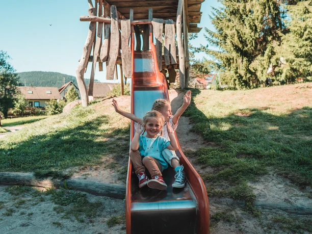 Zwei Kinder sitzen auf der Rutsche auf dem Spielplatz in Klosterreichenbach