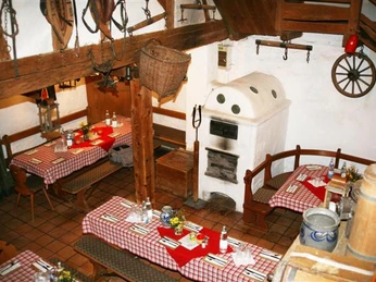 Blick in die gemütliche Vollmer´s Mühle mit Kachelofen, eingedeckten Tischen und alten Arbeitsgeräten