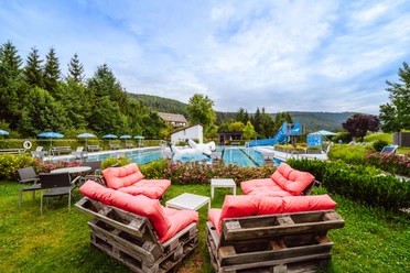 Übersicht über das Freibad mit Sitzecke, Rutsche und Spieltier