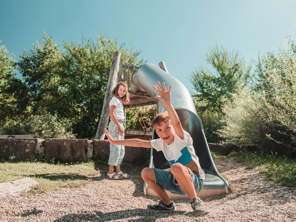 Zwei Kinder stehen neben einer Rutsche