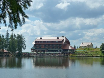 Blick zum Berghotel Mummelsee. Im See spiegelt sich das Hotel und die Bäume