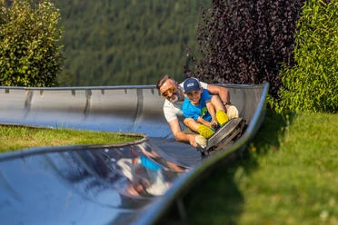 Mann und Junge auf der Sommerrodelbahn Mann und Junge auf der Sommerrodelbahn
