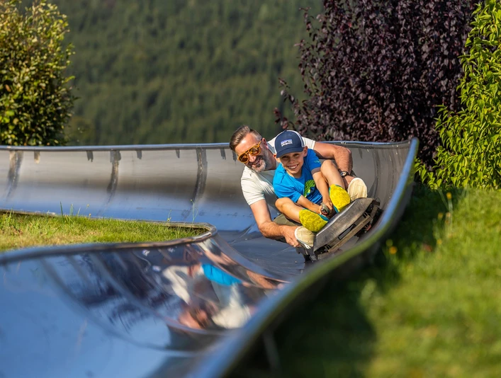 Mann und Junge auf der Sommerrodelbahn Mann und Junge auf der Sommerrodelbahn