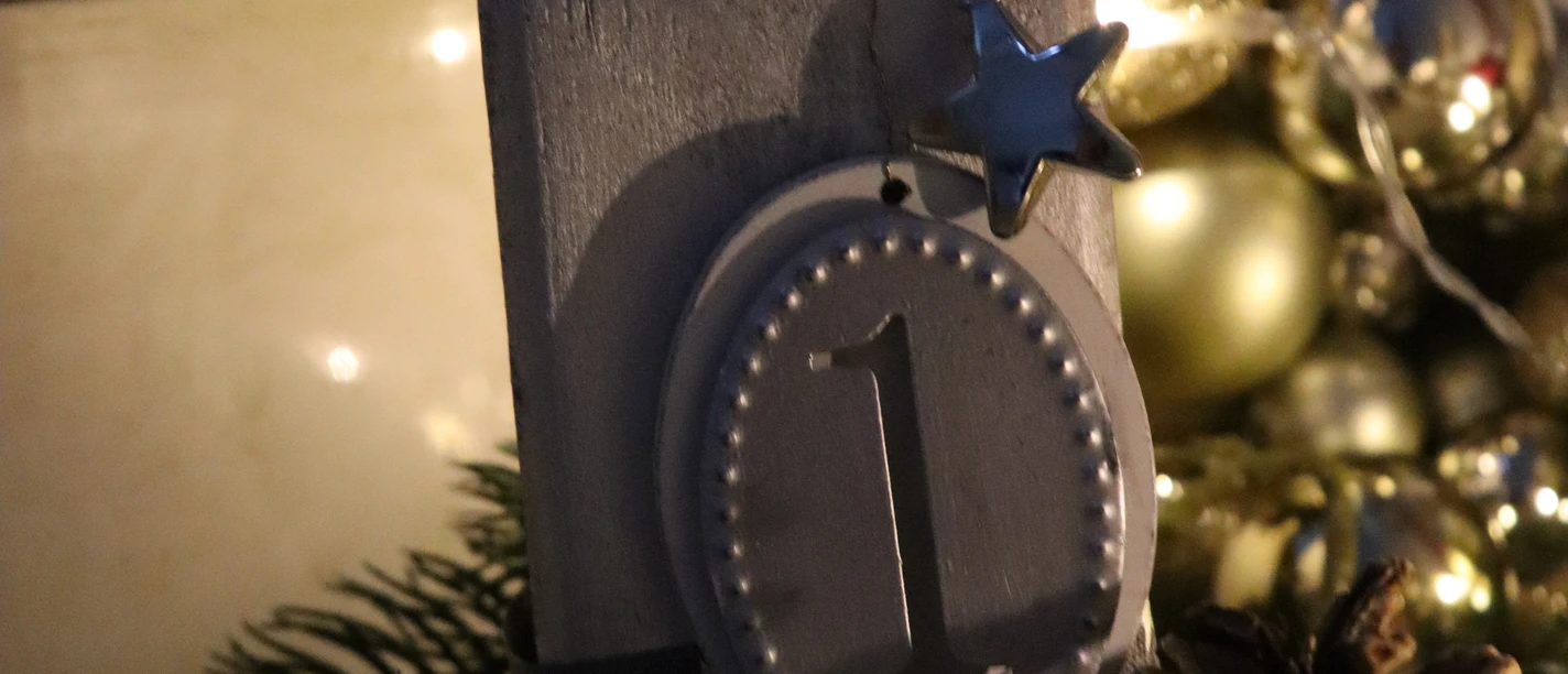Eine festliche Dekoration mit brennender Adventskerze, Tannenzapfen und Weihnachtskugeln.
