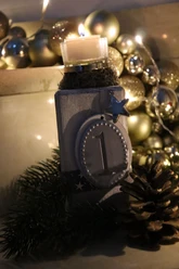Eine festliche Dekoration mit brennender Adventskerze, Tannenzapfen und Weihnachtskugeln.