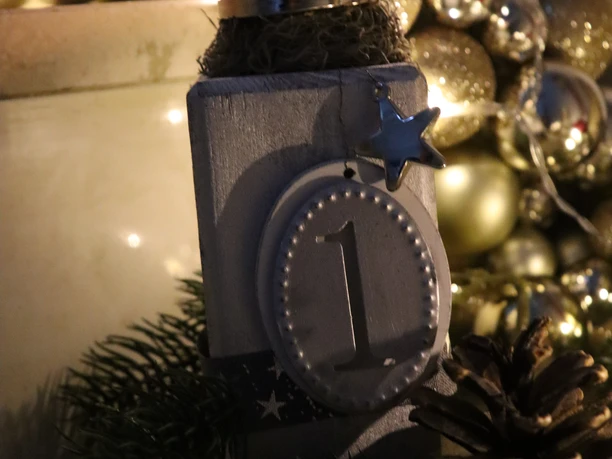 Eine festliche Dekoration mit brennender Adventskerze, Tannenzapfen und Weihnachtskugeln.