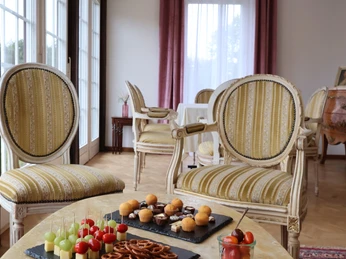 schloss_petershagen_vorraum_2887a.jpg Vornehm eingerichteter Raum mit antiken Stühlen und einem Tisch voller Snacks und Fingerfood.