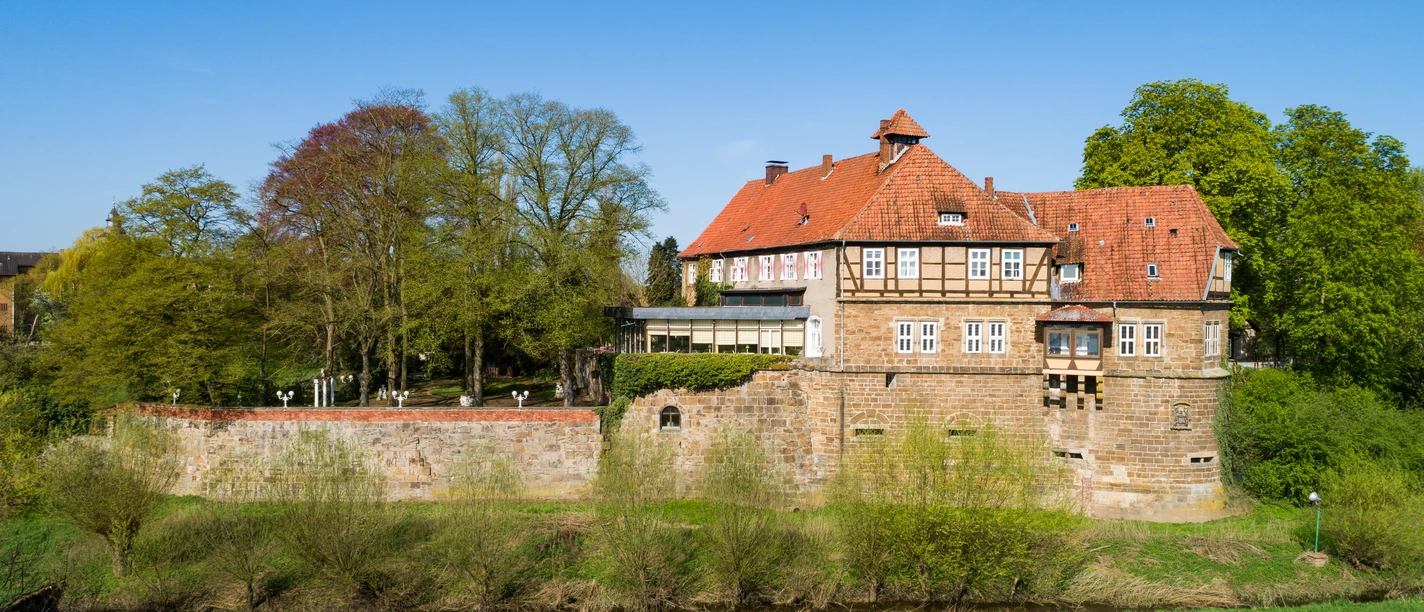 Historisches Schloss Petershagen an der Weser, umgeben von Grünflächen und altem Baumbestand.