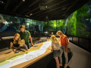 Eltern und Kinder erkunden ein interaktives, multimediales Museum mit naturbezogenen Ausstellungen.