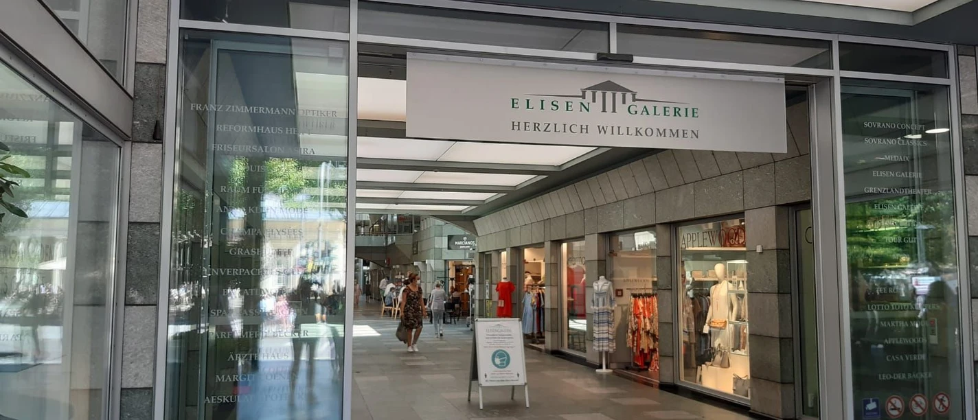 Eingang zu ElisenGalerie mit gläsernen Automatik-Türen und einem Schild, auf dem "ElisenGalerie" steht und das Logo der ElisenGalerie.