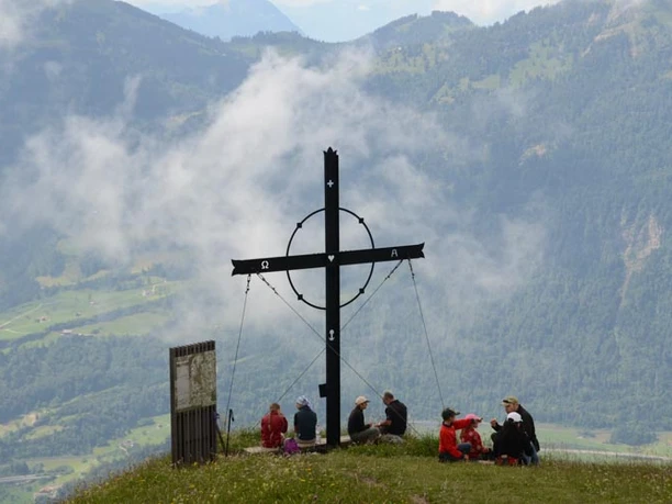 Wanderer geniessen den Gipfel des Gnipen mit dem Gipfelkreuz.