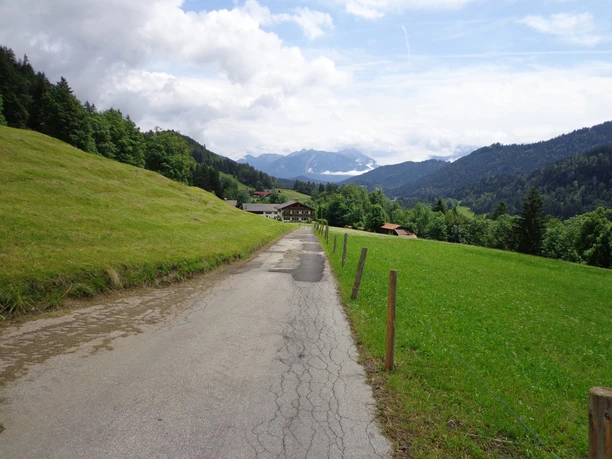 Weg zwischen Pfeifferalm und Gschwandtnerbauer Schmaler Weg zwischen grünen Wiesen mit Blick auf Wälder und ferne Berggipfel