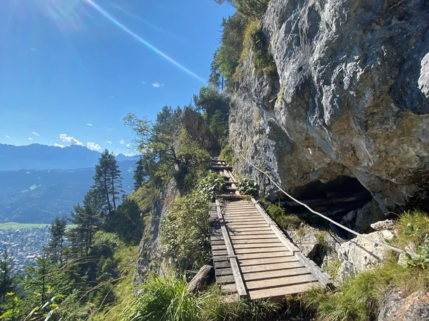 Zur Felsenkanzel am Kramer Schmaler Steg am Felsenhang mit Bergblick und Sonne über bewaldetem Tal.
