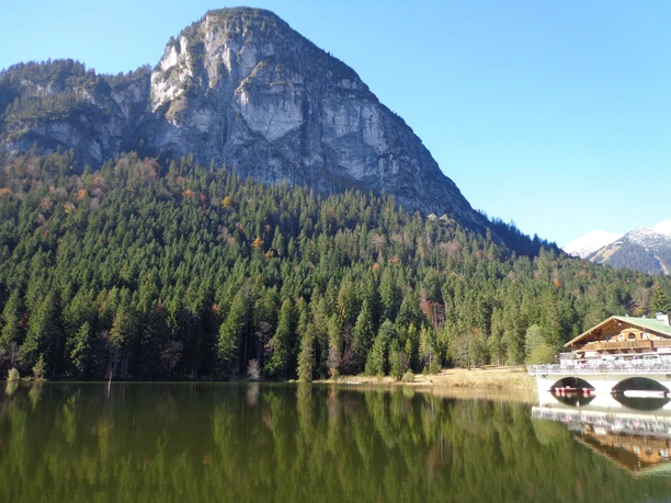 Pflegersee Bergmassiv über dichtem Wald spiegelt sich im ruhigen See mit einem Uferhaus