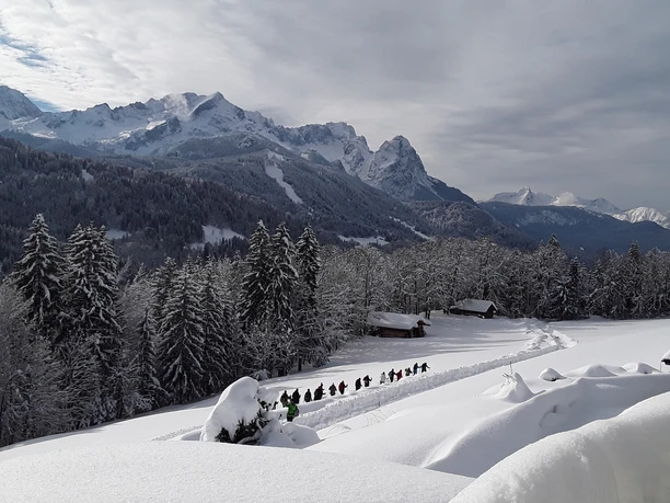 Unterhalb der Pfeifferalm Verschneite Berglandschaft mit einer Gruppe von Schneeschuhwandernden auf einem Pfad.