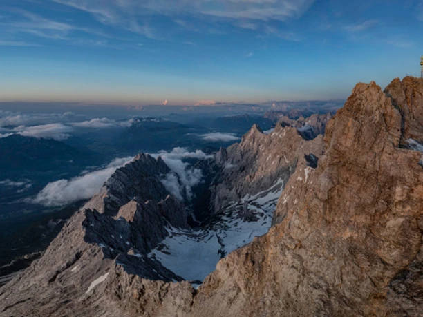 Blick von der Zugspitze Weitreichender Blick über felsige Gipfel, Schneefelder und Wolken unter blauem Himmel
