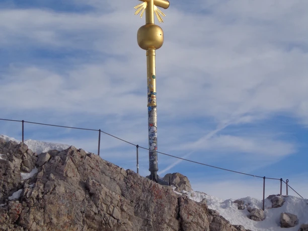 Zugspitzgipfel Goldenes Gipfelkreuz auf felsigem, teils verschneitem Grat unter dünnen Wolken