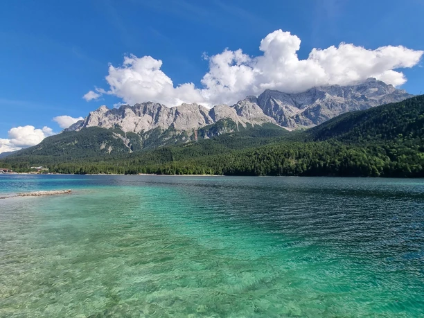 Eibsee Klarer Bergsee mit türkisfarbenem Wasser vor bewaldeten Hängen und felsigen Gipfeln.