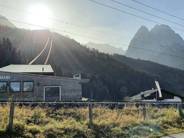 Alpspitzbahn Talstation Talstation der Alpspitzbahn vor bewaldeten Hängen und sonnigem Bergmassiv im Hintergrund
