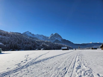 Loipe in Richtung Hammersbach Verschneite Loipe vor markanten Bergen mit verstreuten Hütten und zwei Langläufern.