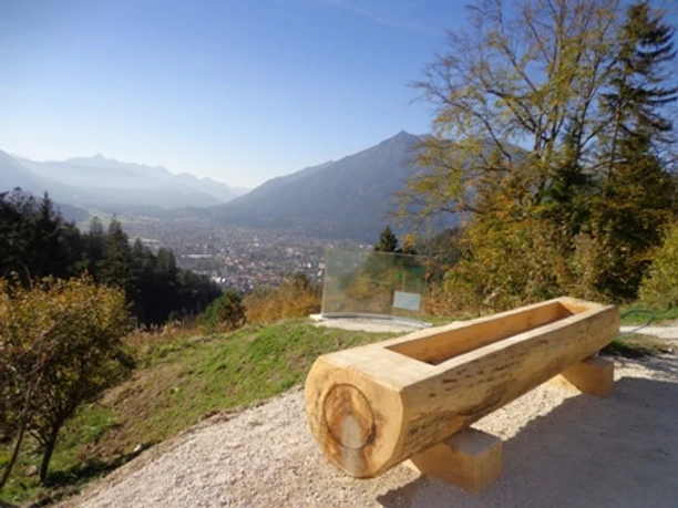 Blick von der Tannenhütte ins Tal Holztrog am Hang mit weitem Talblick vor Bergen unter klarem Himmel.