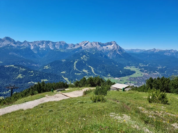 Blick auf Garmisch-Partenkirchen Weite Berglandschaft mit grünen Hängen, Wiesen und Blick ins Tal von Garmisch-Partenkirchen