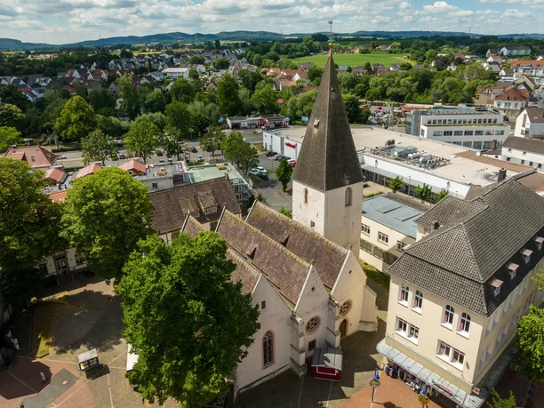 Luftaufnahme der Marktkirche mit ihrem markanten Turm, umgeben von Bäumen und Gebäuden in Detmold.