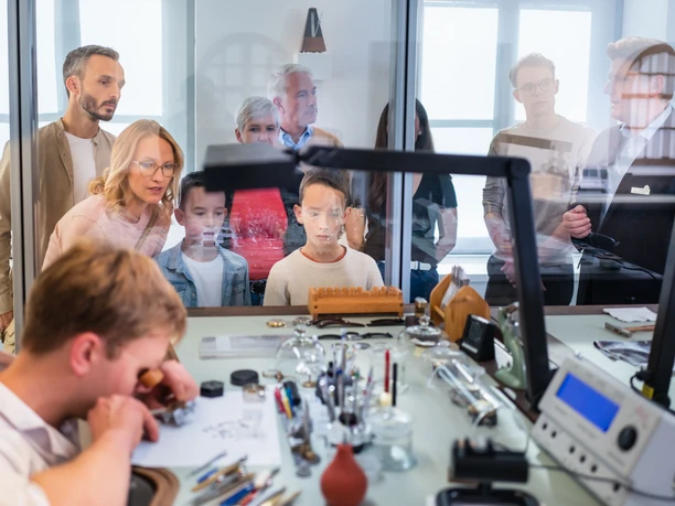 Familienführung im Uhrenmuseum Glashütte 2, Foto René Gaens.jpg Gruppe betrachtet Uhrenmacher bei filigraner Arbeit im Glashütte Museum.