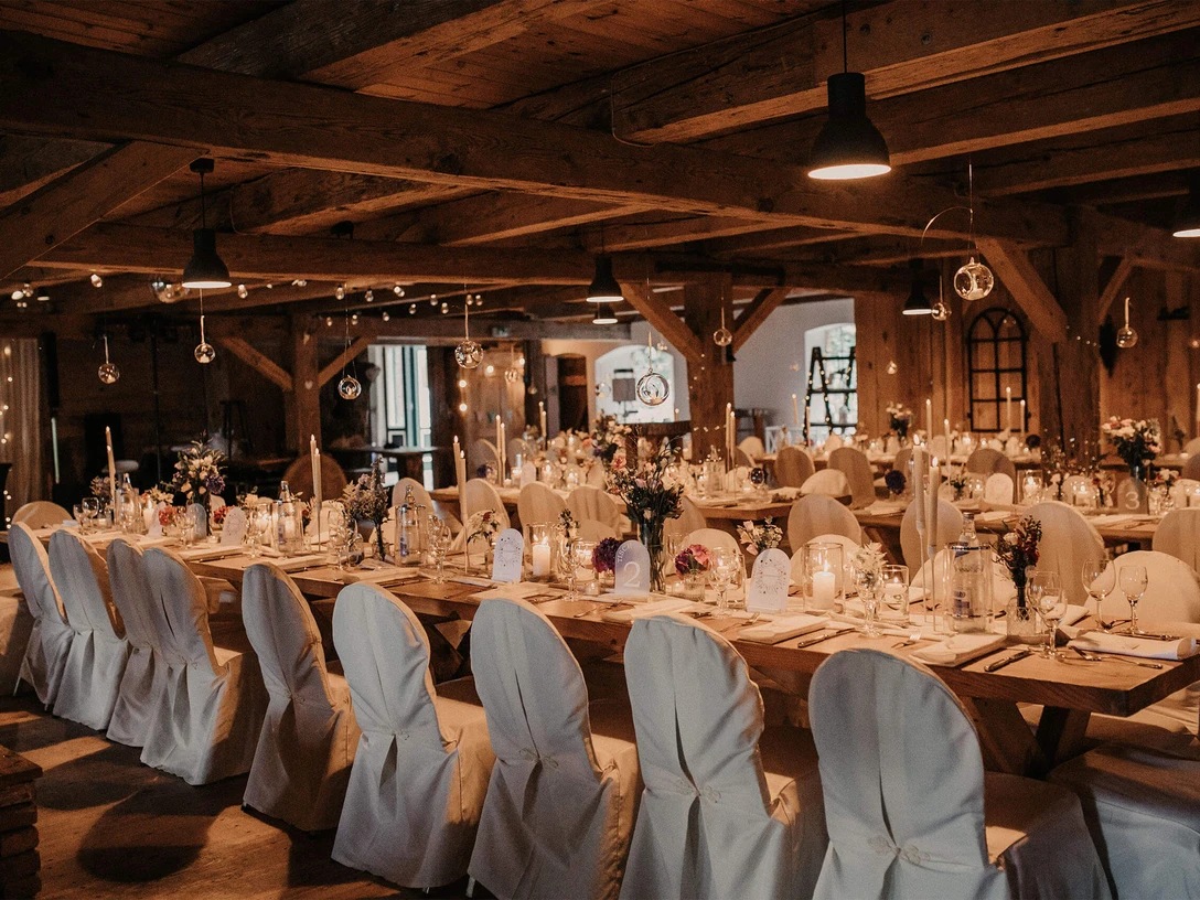 buesum-hochzeitsmesse_web.jpeg Ein langer festlich geschmückter Tisch mit Hussen auf Stühlen.