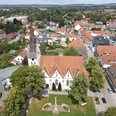 Stadt_Versmold.JPG Luftaufnahme einer Kirche mit rotem Dach, umgeben von Bäumen und Wohnhäusern in einer Stadtlandschaft.