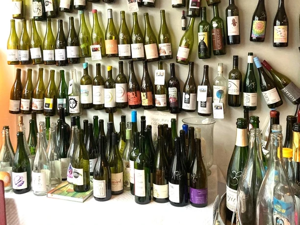 La Vincaillerie A creative arrangement of empty wine bottles displayed on the shelves in a wine store underlines the charm of "La Vincaillerie", which specializes in natural wines.