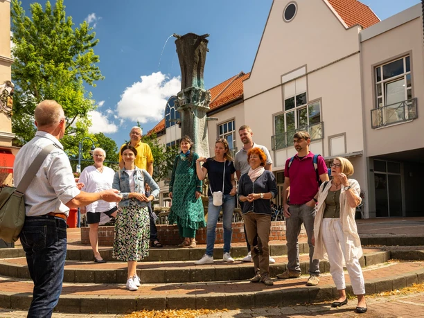 Zieglerbrunnen Eine Gruppe Touristen hört einem Stadtführer vor dem Zieglerbrunnen zu, umgeben von Gebäuden.
