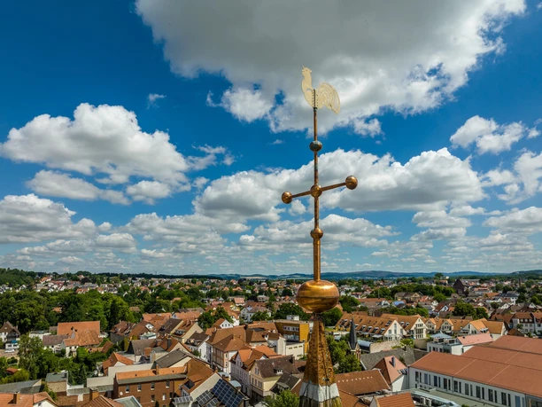 Marktkirche Lage Hahn als Wetterfahne auf Turmspitze mit Blick auf das weitläufige Stadtpanorama von Lage unter blauem Himmel.