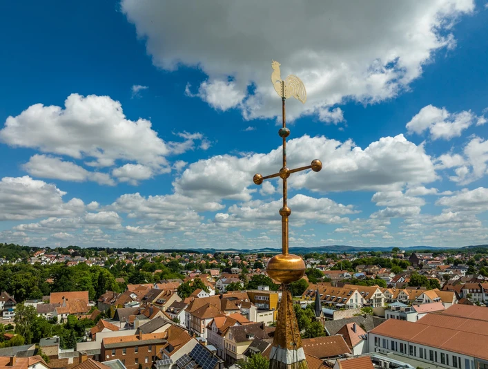 Marktkirche Lage Hahn als Wetterfahne auf Turmspitze mit Blick auf das weitläufige Stadtpanorama von Lage unter blauem Himmel.