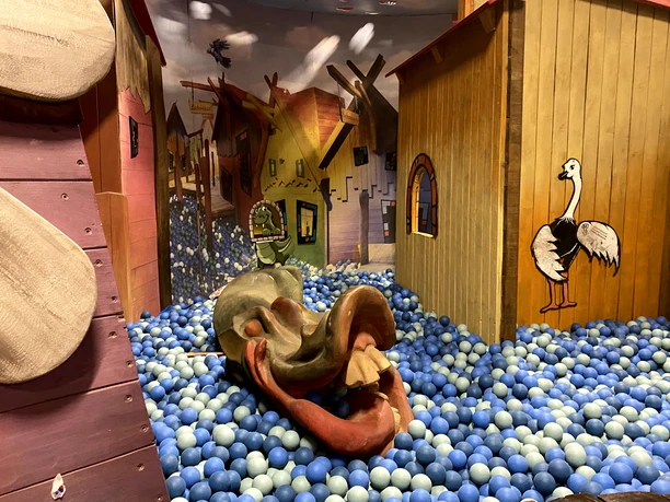 Spielbereich Bunter Indoor-Spielbereich mit Ballpool, Holzhäusern und Tierfiguren für Kinder.