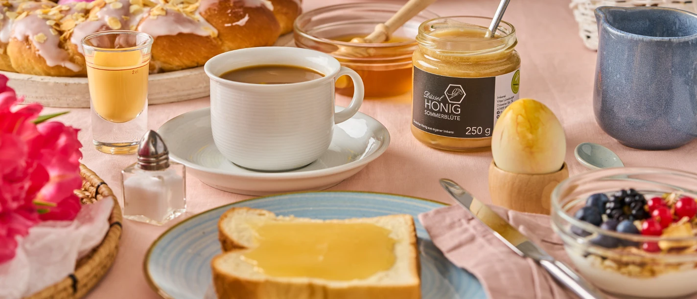 Frühstück im neanderland mit Düssel-Honig Vielfältiges Frühstück mit einer Scheibe Toast und Düssel-Honig, umgeben von Ostergebäck und Kaffee.