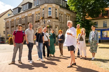 Stadtführung Lage Eine Gruppe besichtigt ein historisches Gebäude, geführt von einem lächelnden Mann in Shorts.