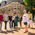 Stadtführung Lage Eine Gruppe besichtigt ein historisches Gebäude, geführt von einem lächelnden Mann in Shorts.