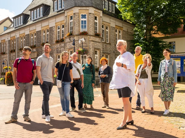 Stadtführung Lage Eine Gruppe besichtigt ein historisches Gebäude, geführt von einem lächelnden Mann in Shorts.