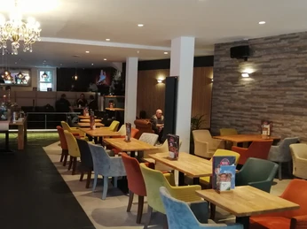 Herford-Piccoli-Pro Herford GmbH.jpg Ein modernes Café mit vielseitigen Sitzmöglichkeiten und einer einladenden Atmosphäre.