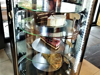 Eine beleuchtete Kuchenvitrine mit verschiedenen Tortenstücken, darunter eine Himbeer-Joghurt-Torte.