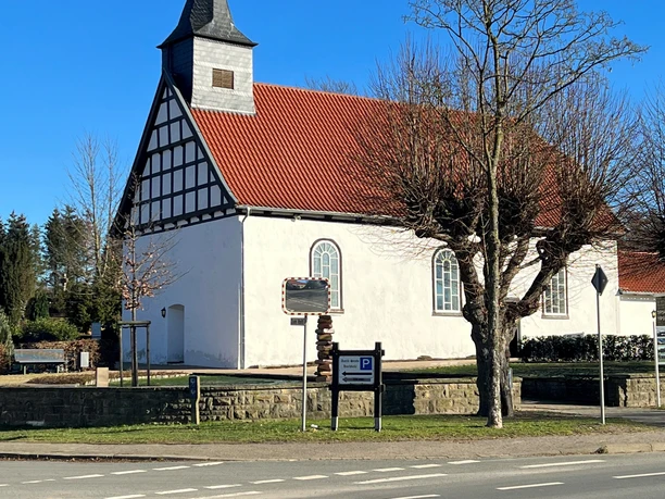 Die Heilig-Kreuz-Kapelle Haldem hat ein rotes Ziegeldach und Fachwerkelemente an den Giebelseiten.