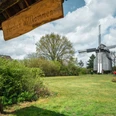 Bockwindmühle Oppenwehe Christoph Partsch (1).jpg Holz-Bockwindmühle in Landschaft mit grüner Wiese und Leuten, darunter ein Schild mit "Herzlich Willkommen".